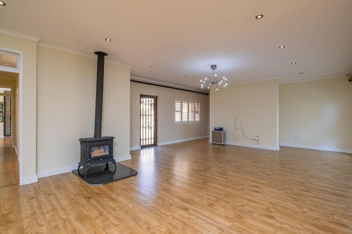 Spacious living room featuring light wood-look laminate flooring, a freestanding fireplace, recessed lighting, and window shutters, offering a bright and versatile open-plan layout.