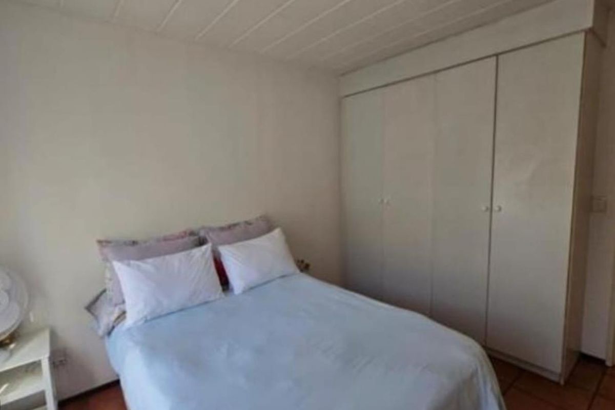 A bedroom featuring built-in cupboards, tiled flooring, and a simple ceiling light fixture.