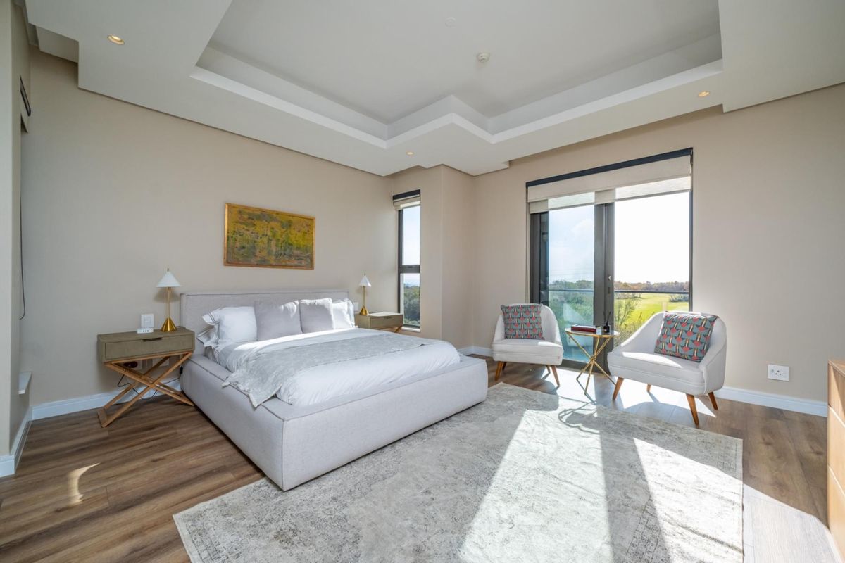 Spacious bedroom featuring a modern tray ceiling, recessed lighting, and large windows with access to a private balcony and scenic views.