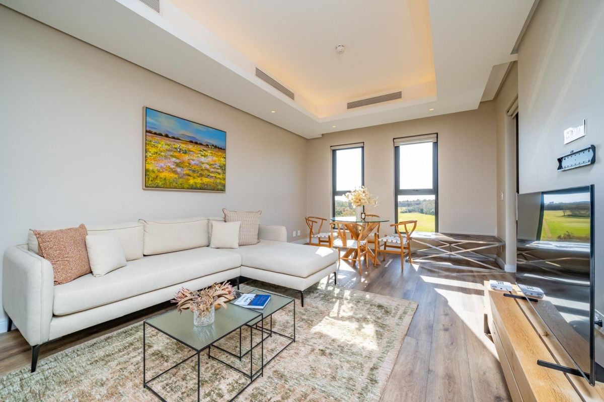 A bright and modern living room featuring laminate flooring, recessed ceiling lighting, ducted air conditioning, and large windows with scenic views.