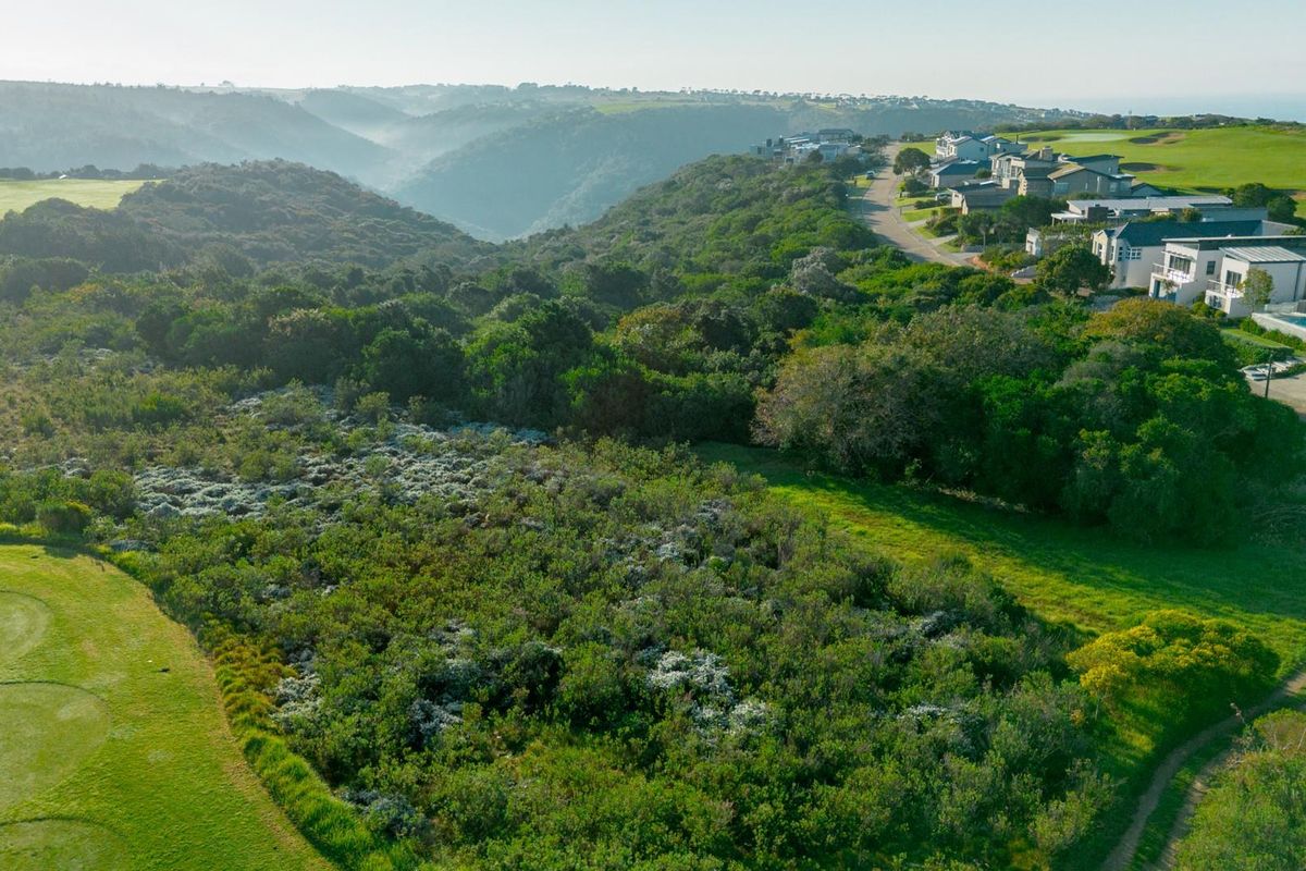 Aerial view of a vacant residential plot situated adjacent to a golf course and established residential estate.