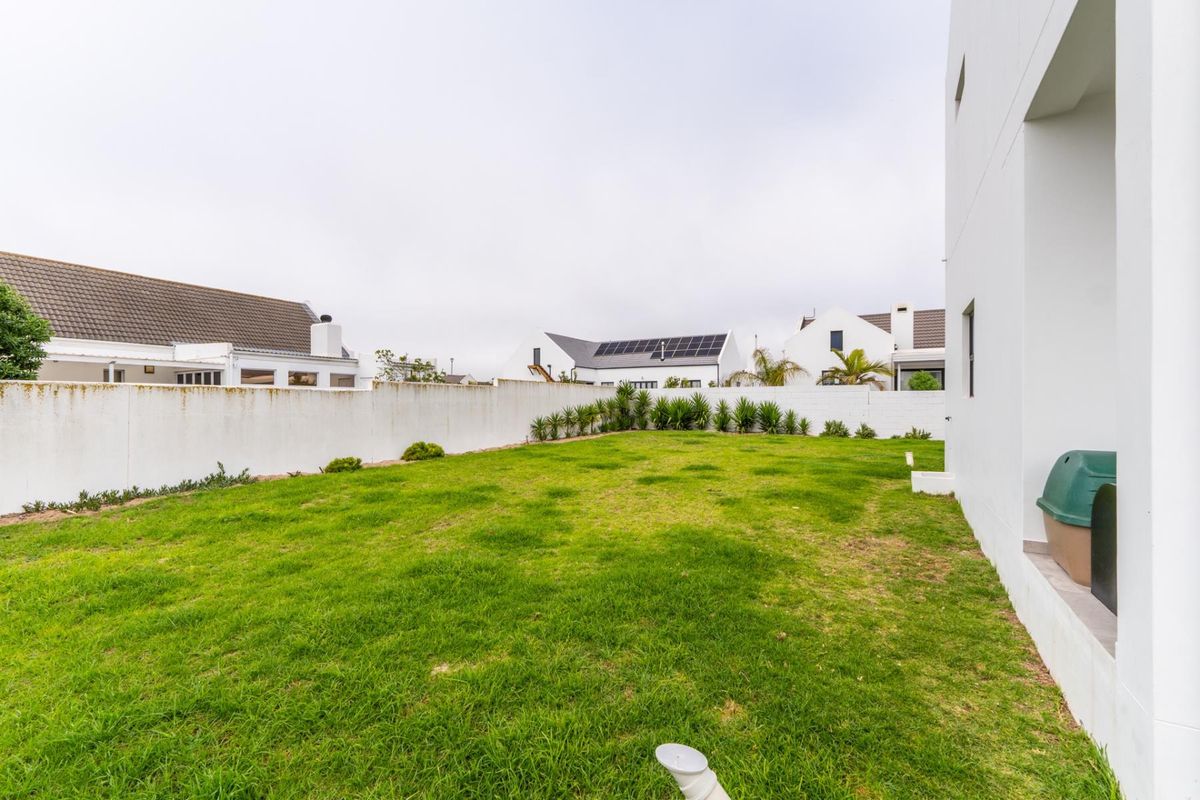 A private rear garden featuring a level lawn area enclosed by a perimeter boundary wall.