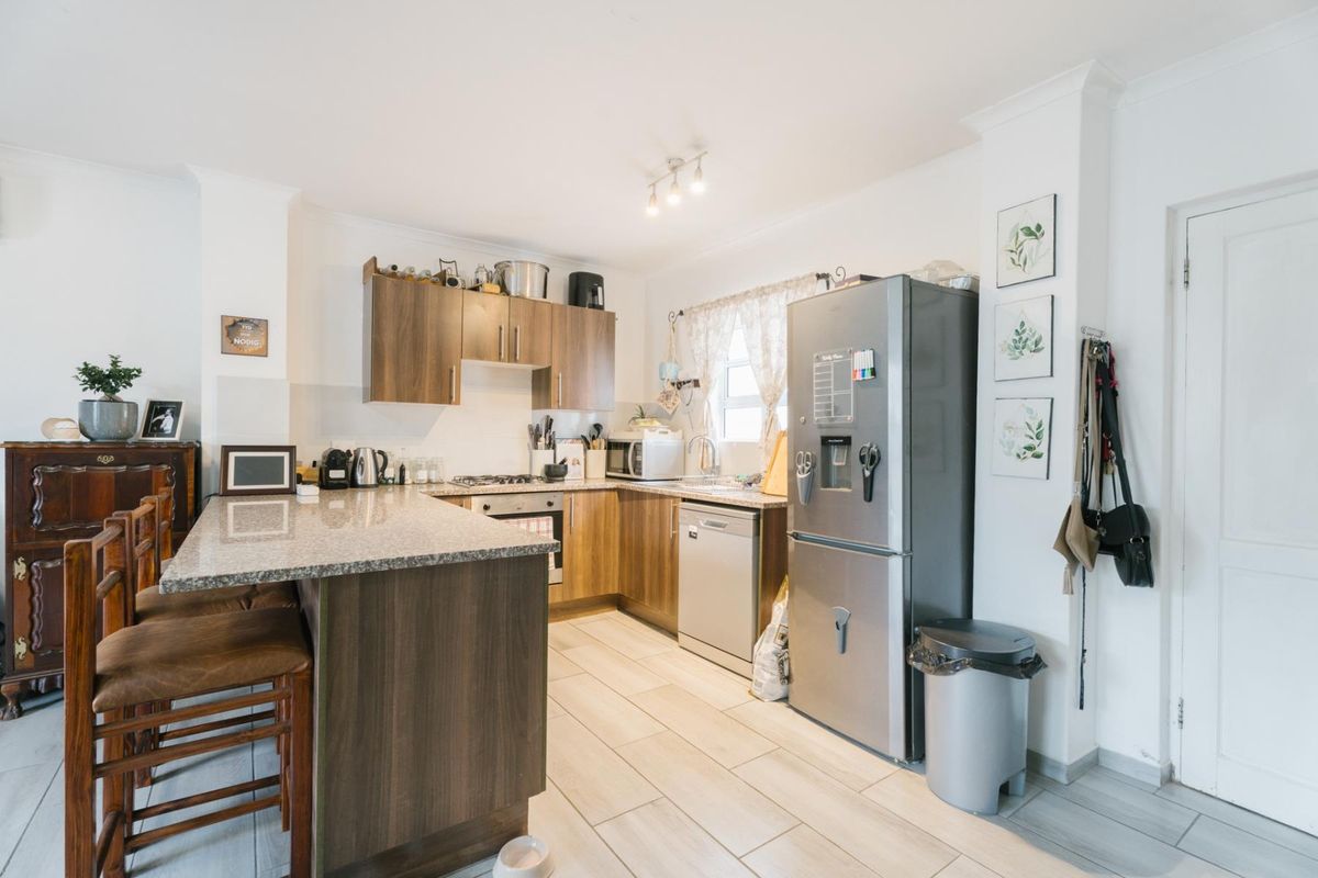 A functional kitchen featuring wood-look cabinetry, granite countertops, a breakfast nook, and tiled flooring, providing a practical and well-maintained cooking space.