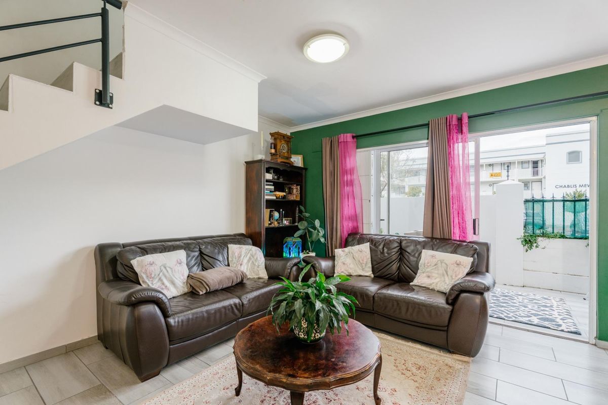 A living room featuring tiled flooring, a staircase, and a sliding glass door providing access to an outdoor patio area.