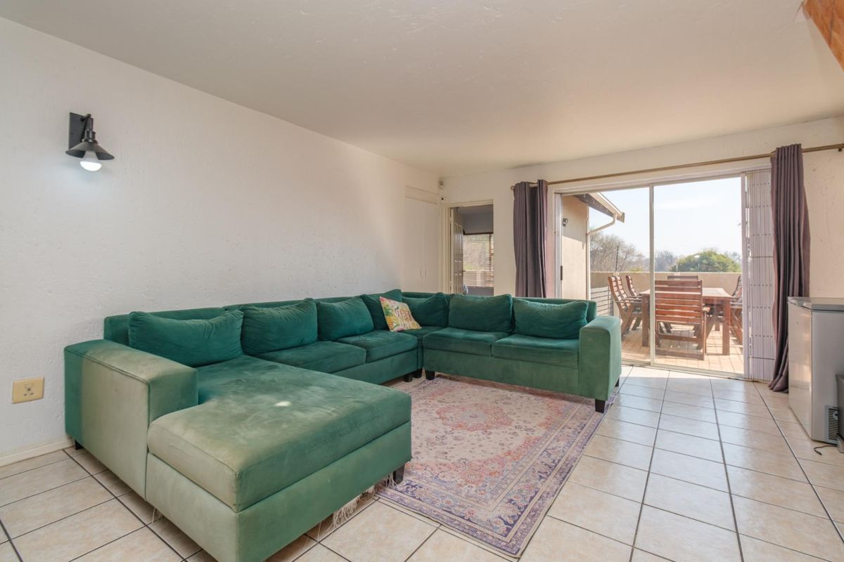 A living room featuring tiled flooring and a large sliding glass door providing direct access to an outdoor patio area.