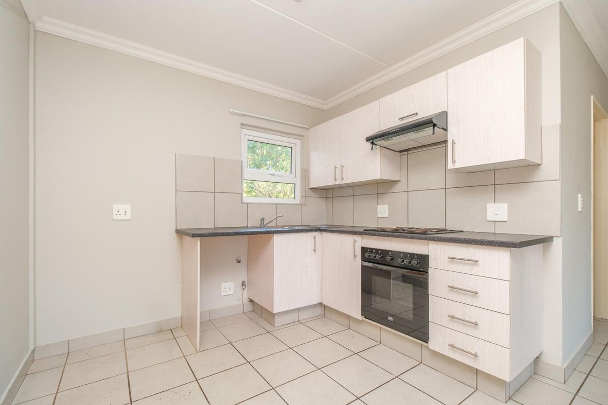 A clean, functional kitchen featuring light-toned cabinetry, built-in oven and hob, tiled splashbacks, and tiled flooring in a neutral, well-maintained space.