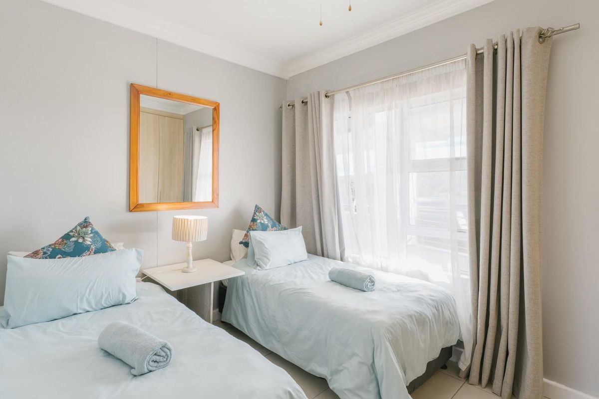 A well-maintained bedroom featuring neutral wall tones, tiled flooring, decorative cornice, and a built-in cupboard, offering a bright and comfortable living space.
