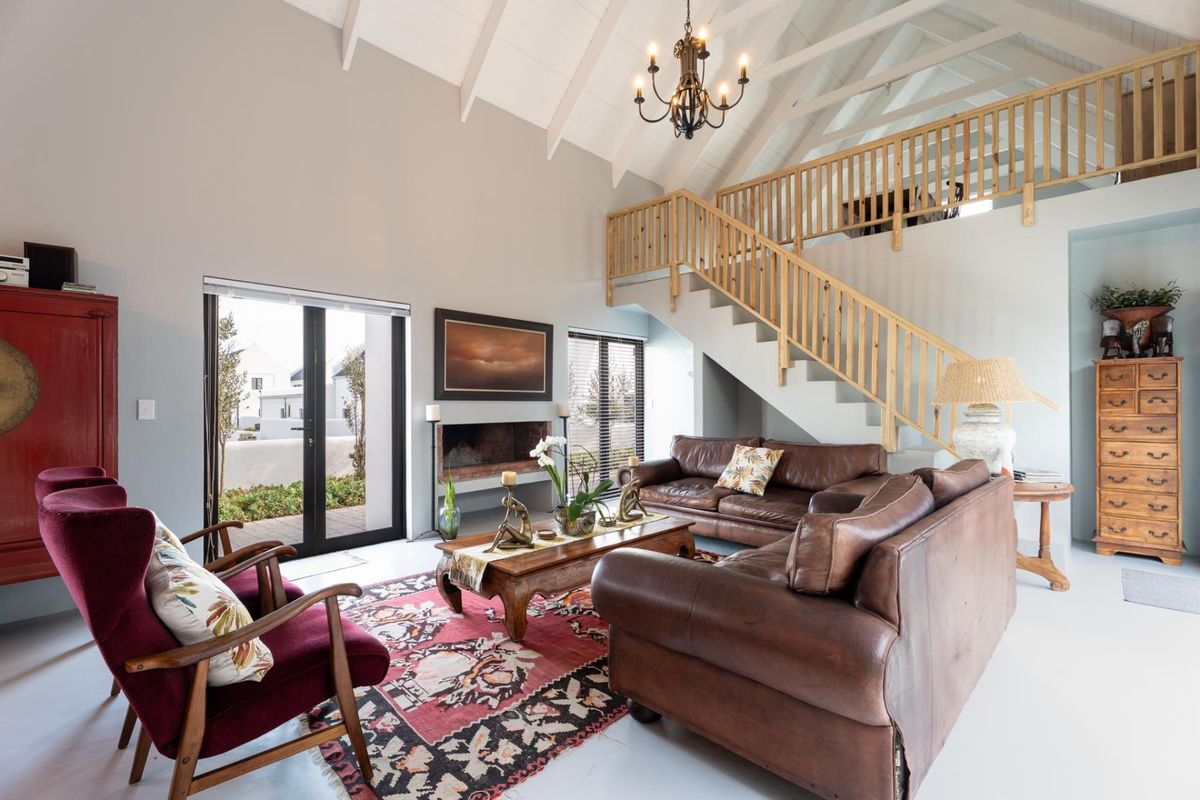 Spacious living room featuring a vaulted ceiling with exposed rafters, a built-in fireplace, and a staircase leading to a mezzanine level.