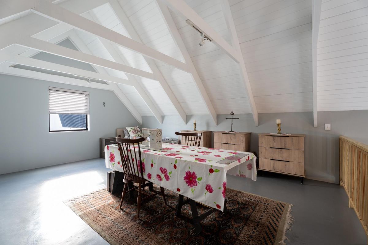 Spacious attic-style bedroom featuring a vaulted ceiling with exposed white timber rafters, painted concrete flooring, and a timber balustrade.