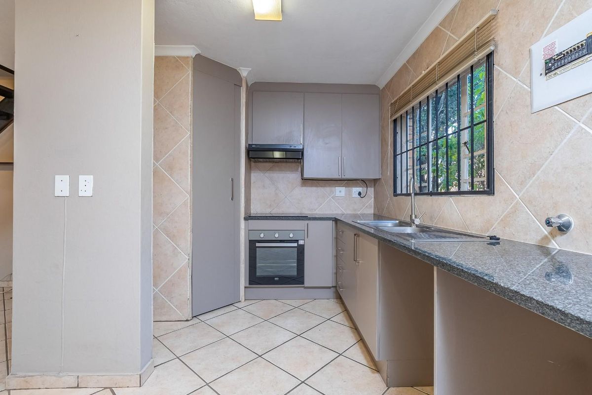 A functional kitchen featuring granite countertops, built-in cabinetry, an integrated oven, and a tiled splashback, offering a clean and practical workspace.