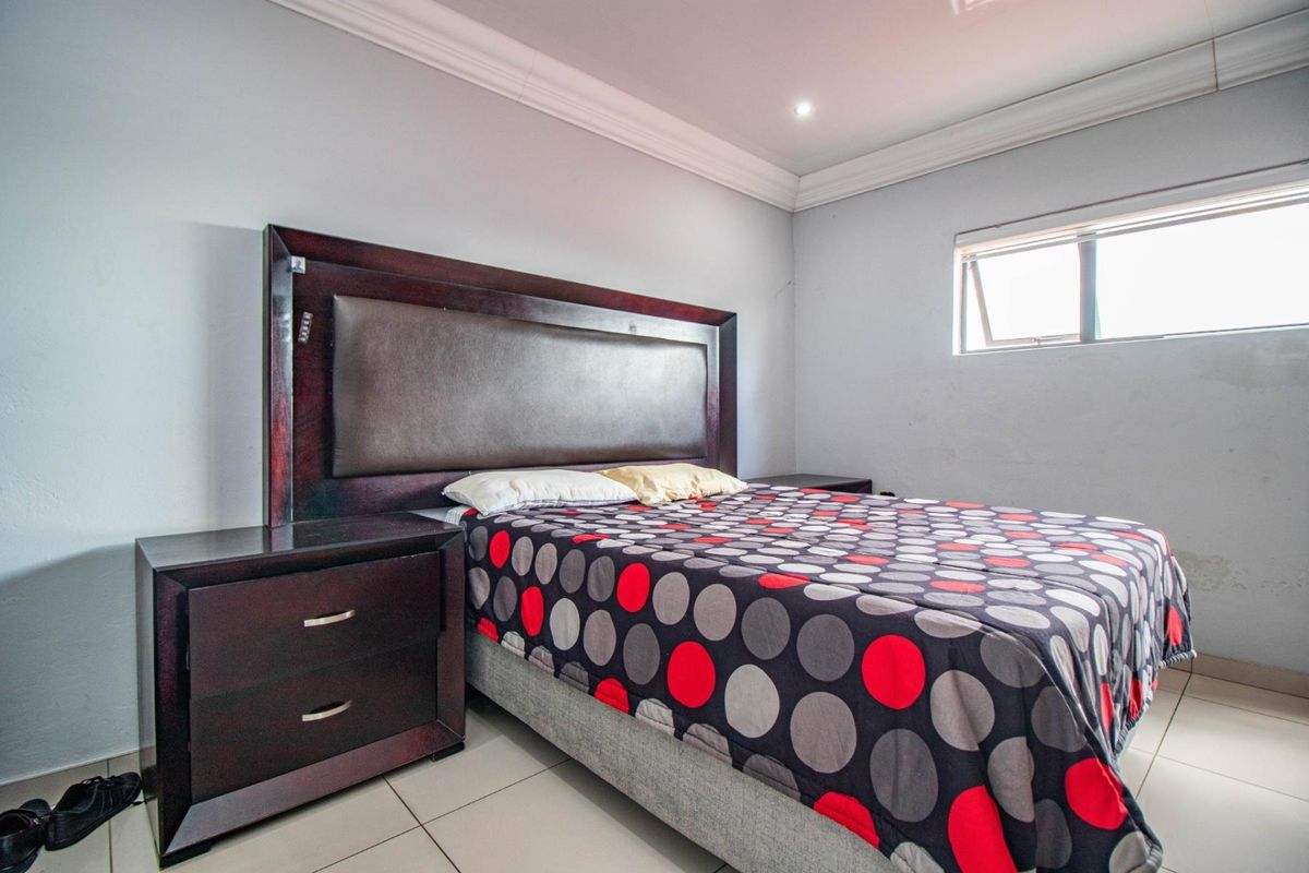 A functional bedroom featuring tiled flooring, a cove ceiling, and an awning window, providing a neutral base for potential interior updates.