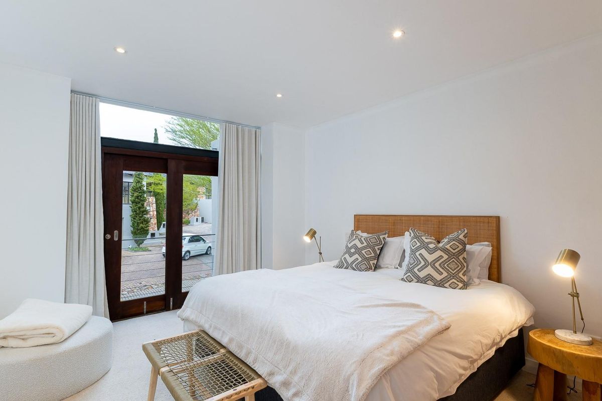 A bright and modern bedroom featuring recessed downlighting and a large glass door providing natural light and access to the exterior.