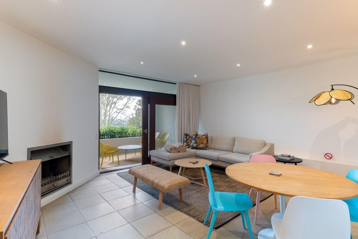 Open-plan living and dining area featuring tiled floors, a built-in fireplace, and direct access to a private balcony through sliding glass doors.