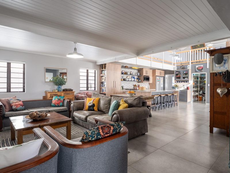 Spacious open-plan living area featuring a modern kitchen with island, tiled floors, and a mezzanine level, creating a bright and airy atmosphere.
