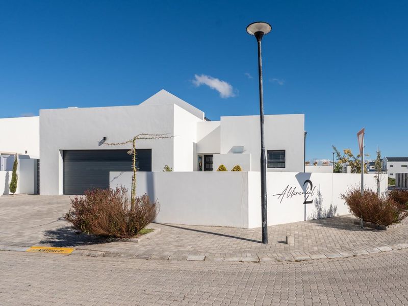 Modern single-story residential property featuring a clean white facade, integrated garage, and paved driveway in a well-maintained estate setting.