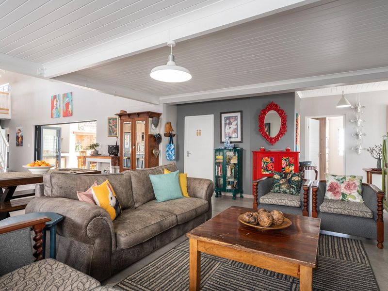 Spacious open-plan living area featuring exposed beam ceilings, tiled flooring, and a timber staircase leading to an upper level.