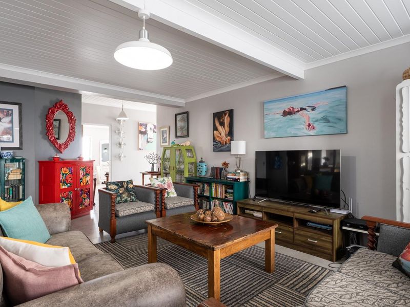 A comfortable living room featuring a white tongue and groove ceiling with an exposed beam and central pendant lighting.