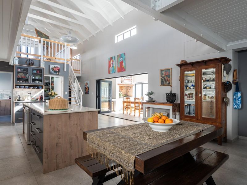 Spacious open-plan living and kitchen area featuring a vaulted ceiling with exposed beams, a central kitchen island, and seamless access to the outdoor patio.