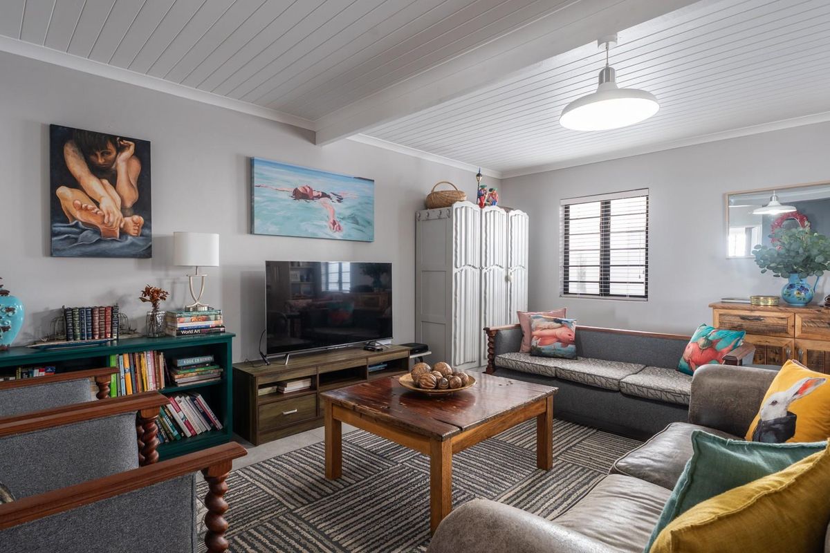 A comfortable living room featuring a tongue and groove ceiling, pendant lighting, and a window with fitted blinds.