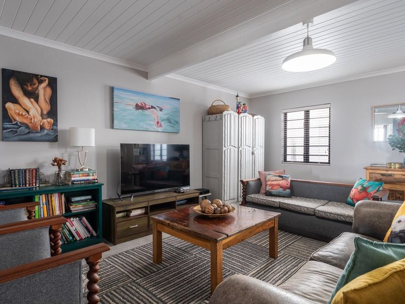 A comfortable living room featuring a tongue and groove ceiling, pendant lighting, and a window with fitted blinds.