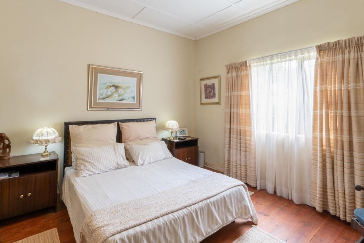 A bedroom featuring warm timber flooring and a tiled ceiling, offering a comfortable and traditional living space.