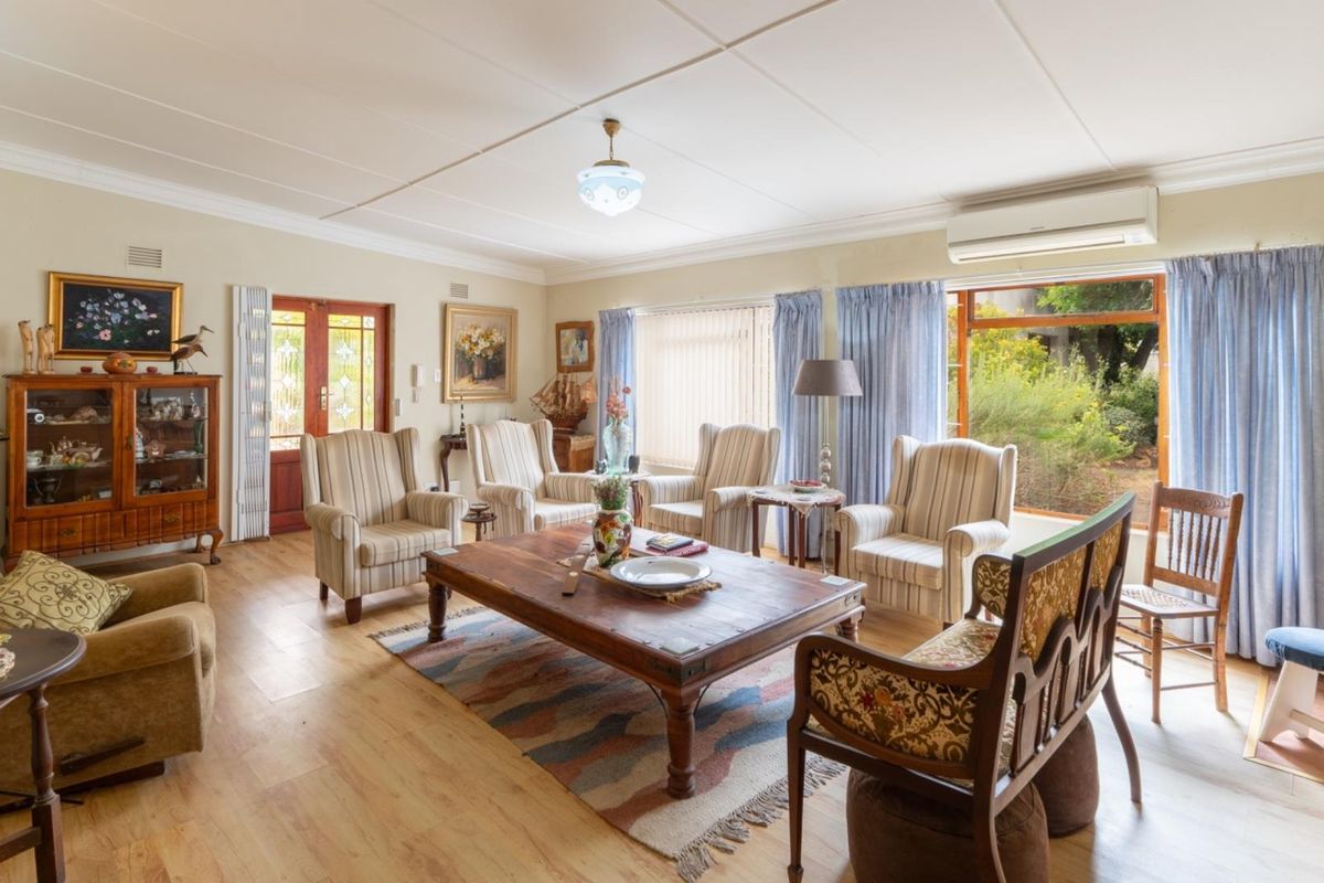 A spacious living room featuring timber-look flooring, a split-system air conditioner, and large glass doors providing natural light and garden access.
