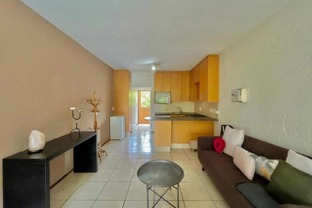 Open plan living area featuring a functional kitchen with built-in cabinetry and tiled flooring, offering a versatile space for living and dining.