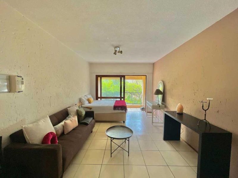 Open-plan living and sleeping area featuring tiled flooring and a sliding glass door providing access to a balcony.