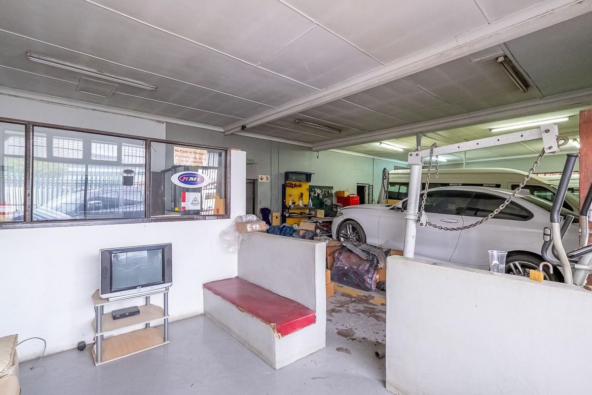 A functional garage space featuring a partitioned office area, concrete flooring, and built-in seating, suitable for automotive or workshop use.