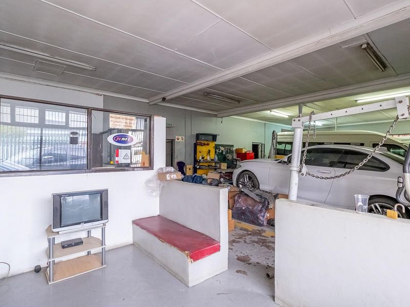 A functional garage space featuring a partitioned office area, concrete flooring, and built-in seating, suitable for automotive or workshop use.