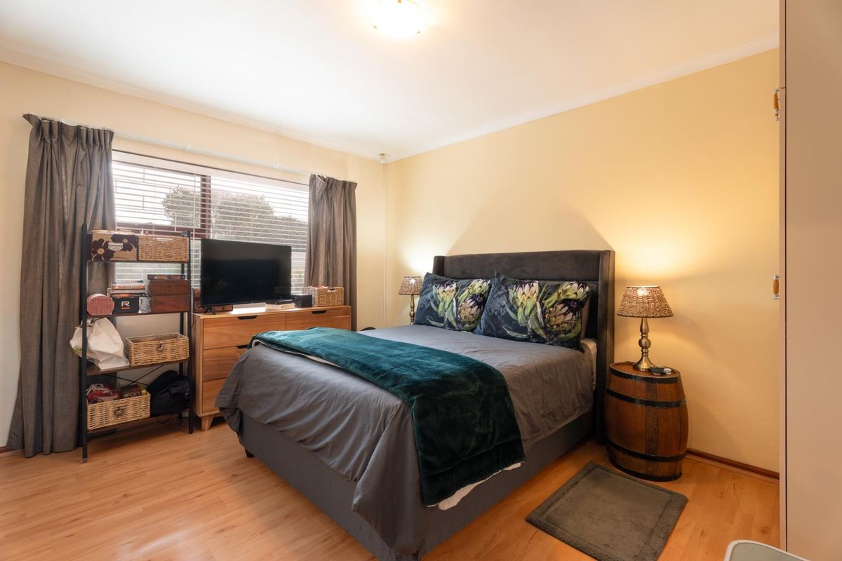 A well-lit bedroom featuring laminate flooring, neutral wall finishes, and a built-in wardrobe, offering a comfortable and functional living space.