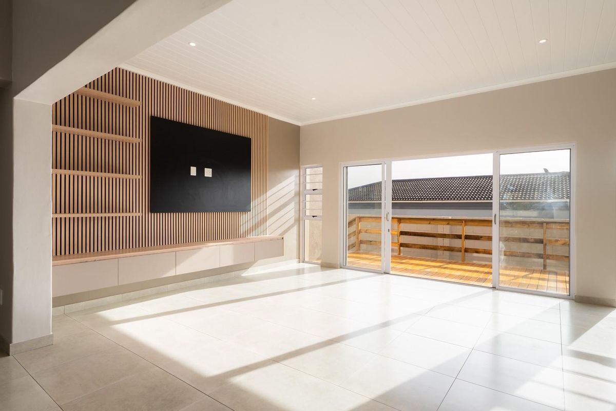 Bright and modern living area featuring a stylish slatted timber feature wall, built-in cabinetry, tiled floors, and large sliding doors opening onto a timber deck.