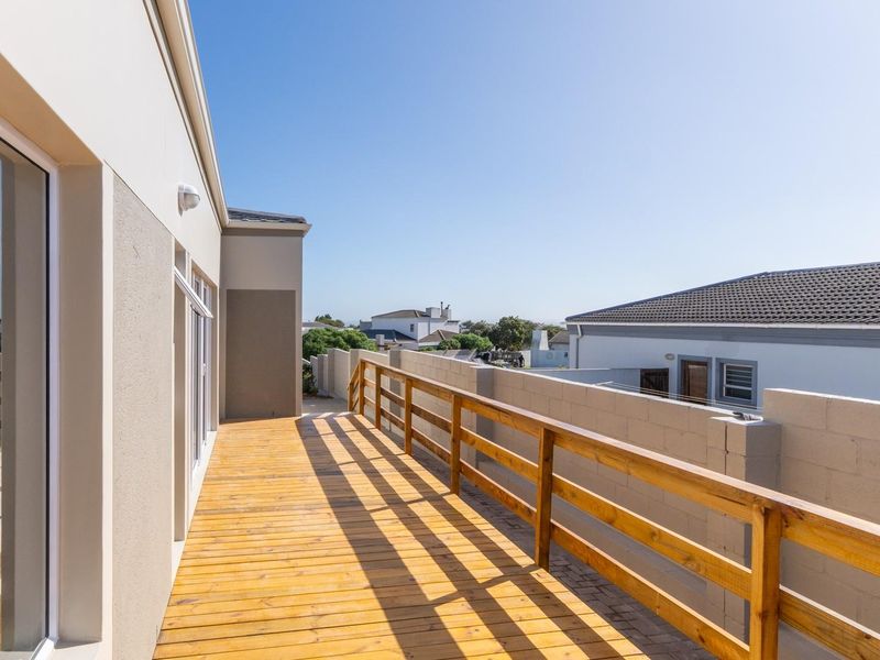 A spacious elevated timber balcony featuring a wooden balustrade, accessible via large sliding glass doors, offering a clear outdoor living space.