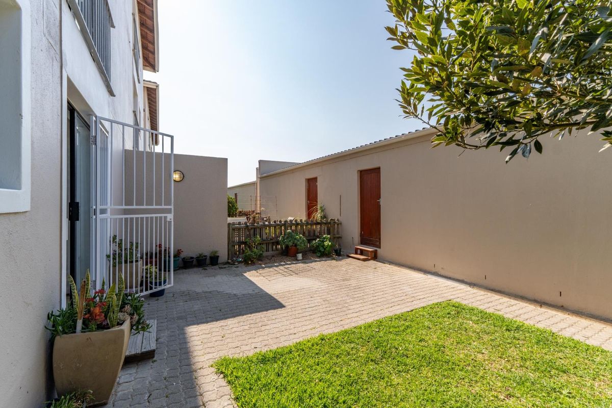 A private rear courtyard featuring paved flooring, a small lawn area, and secure access points to the apartment.