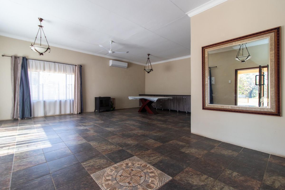 Spacious living area featuring dark tiled flooring, a wood-burning stove, built-in cabinetry, and a split-system air conditioner, offering a versatile open-plan layout.
