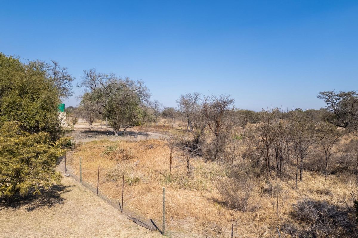 An aerial view of the farm property showing open veld, natural vegetation, wire fencing, and a water tank in the distance.