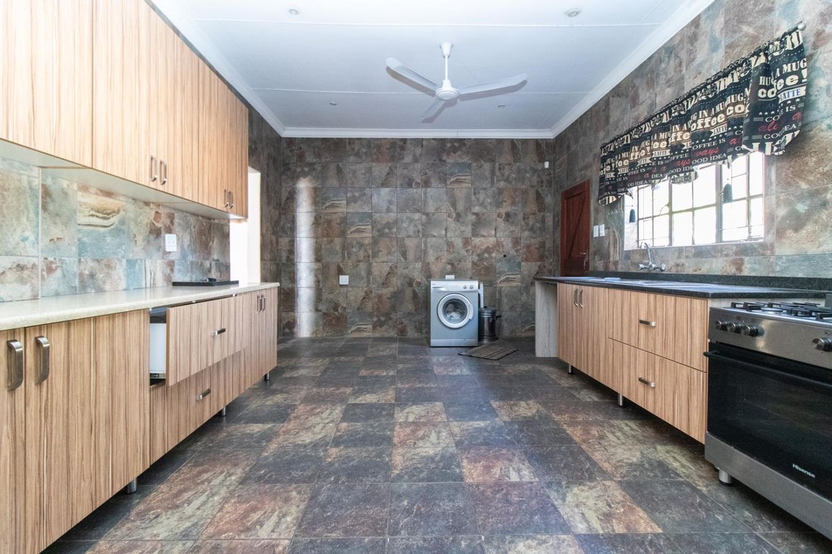 Spacious kitchen featuring extensive built-in cabinetry, stone tile finishes, and integrated laundry plumbing, offering a functional layout with ample workspace.