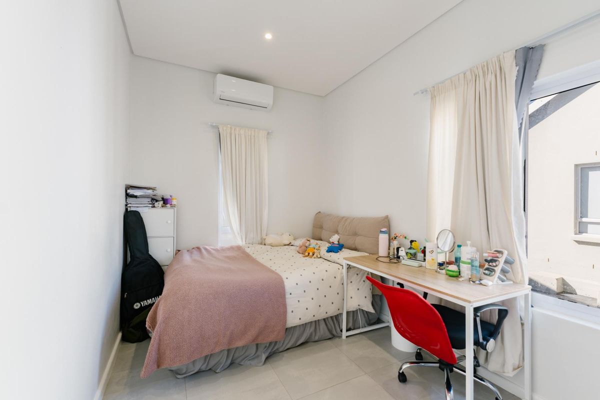 A well-maintained bedroom featuring neutral tiled flooring, recessed lighting, and a wall-mounted split-system air conditioning unit.