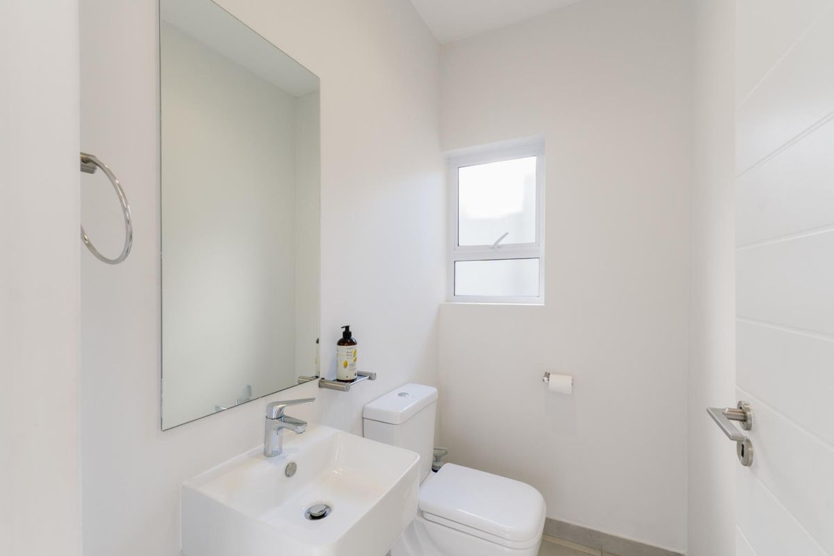 A clean and modern guest bathroom featuring a wall-mounted basin, chrome fixtures, and a minimalist design.