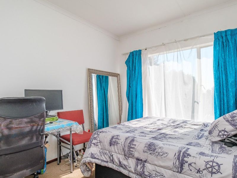 A functional bedroom featuring a large window with curtain tracks, providing natural light and a view of the exterior.