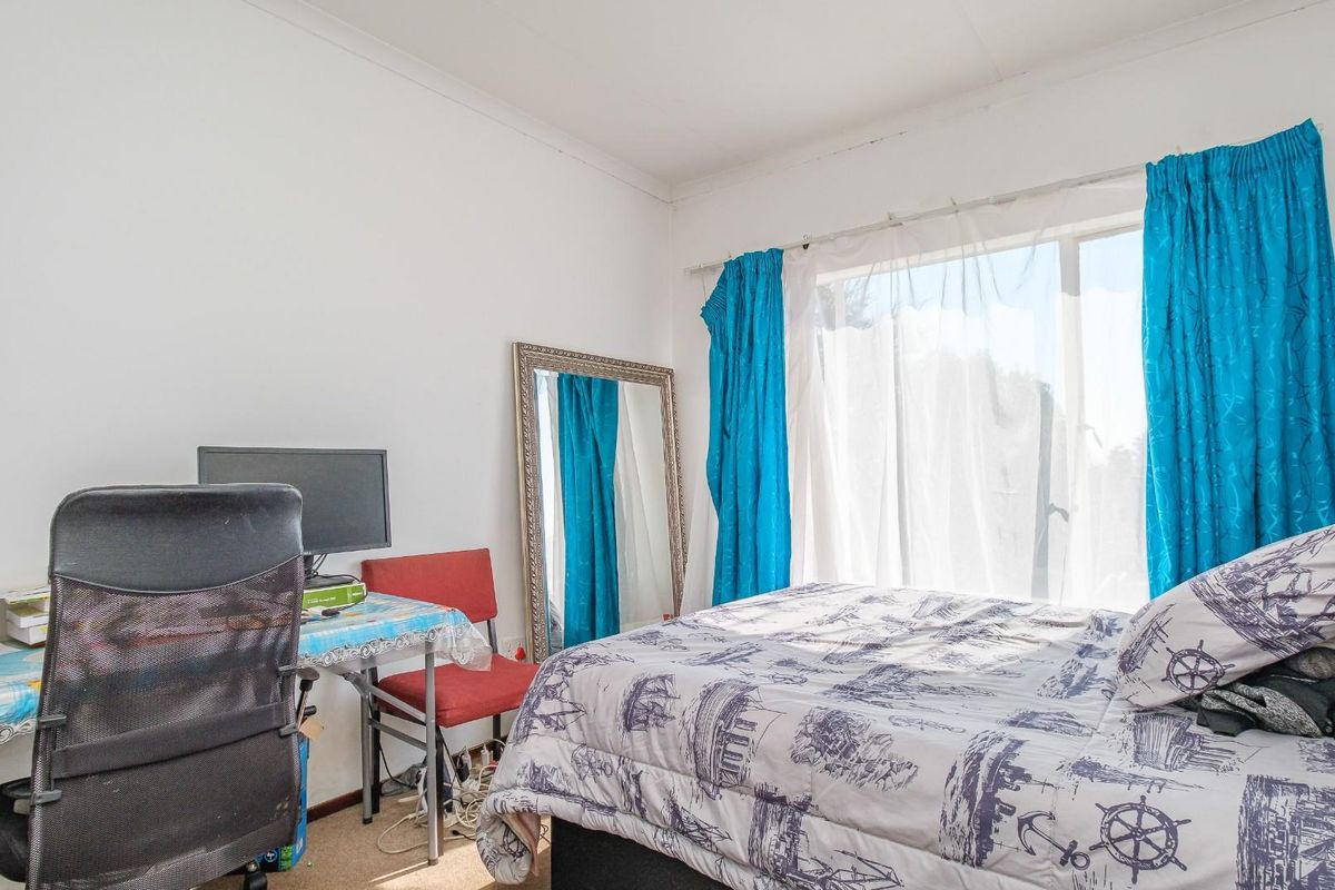 A functional bedroom featuring a large window with curtain tracks, providing natural light and a view of the exterior.