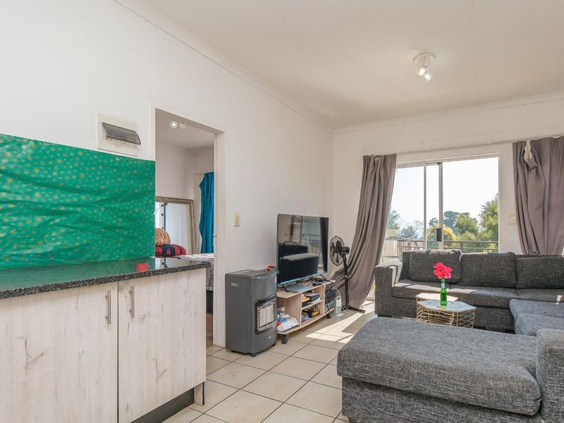Open plan living area featuring tiled flooring, built-in cabinetry with granite countertop, and sliding glass doors leading to an outdoor balcony.