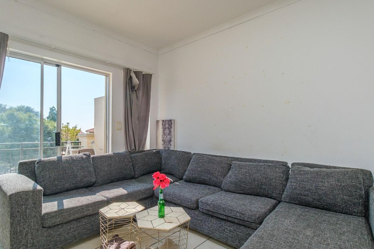 A living room featuring tiled flooring and a sliding glass door providing access to an outdoor balcony area.