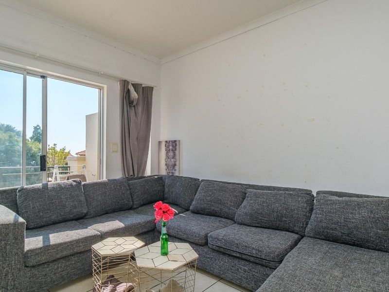 A living room featuring tiled flooring and a sliding glass door providing access to an outdoor balcony area.
