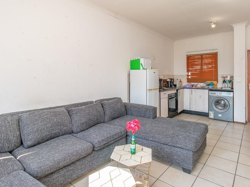 Open-plan living area featuring a compact kitchen with built-in cabinetry, oven, and tiled flooring, seamlessly connected to the lounge space.