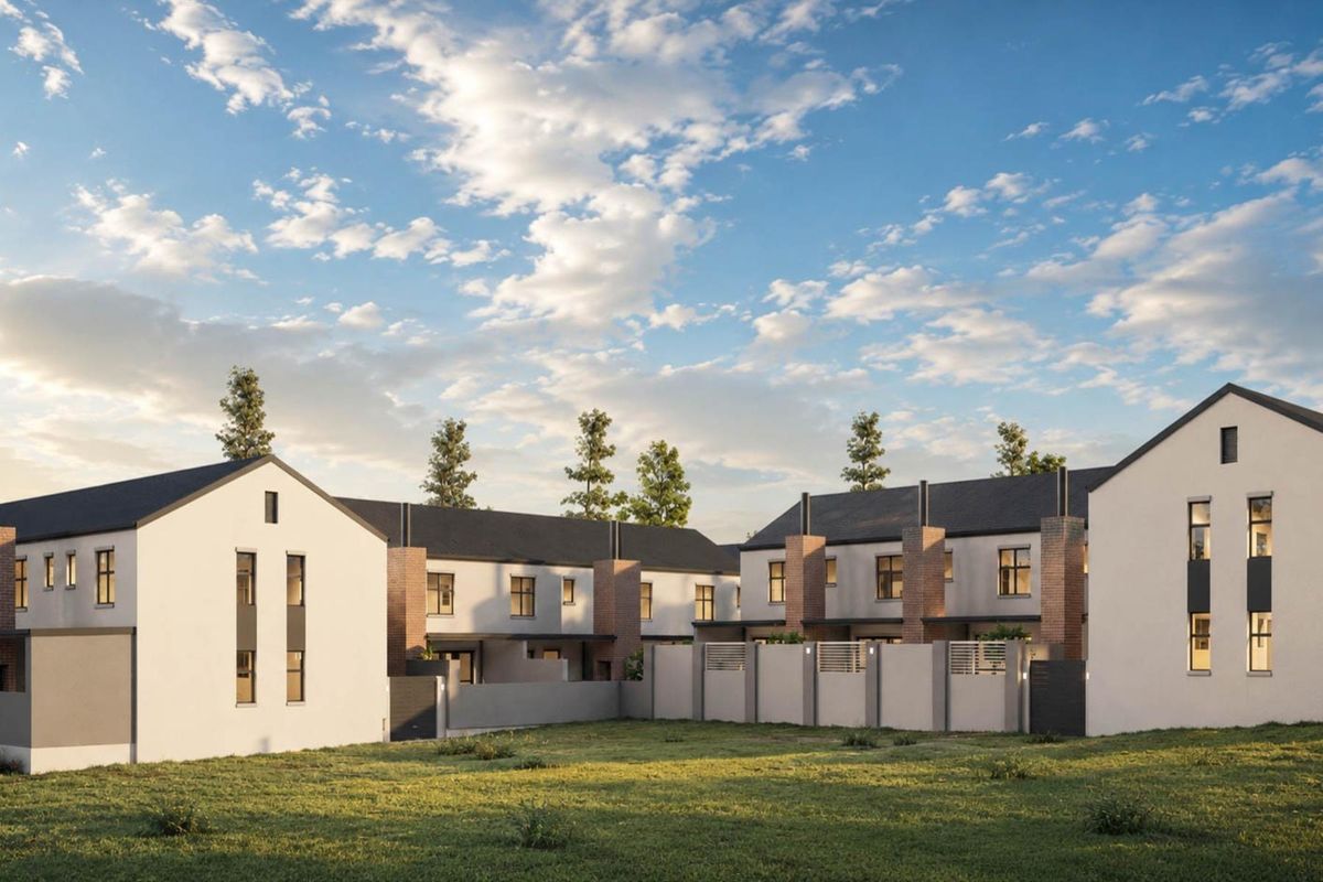 A modern townhouse development featuring clean architectural lines, pitched roofs, brick accents, and secure boundary walls set against a landscaped lawn.