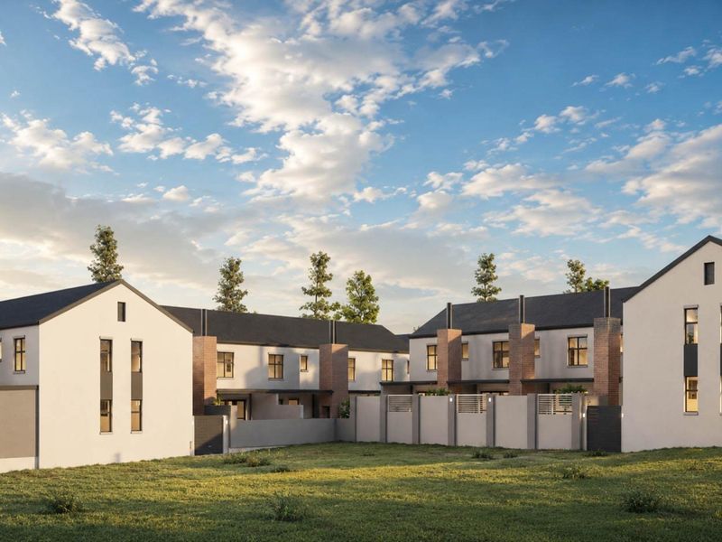 A modern townhouse development featuring clean architectural lines, pitched roofs, brick accents, and secure boundary walls set against a landscaped lawn.