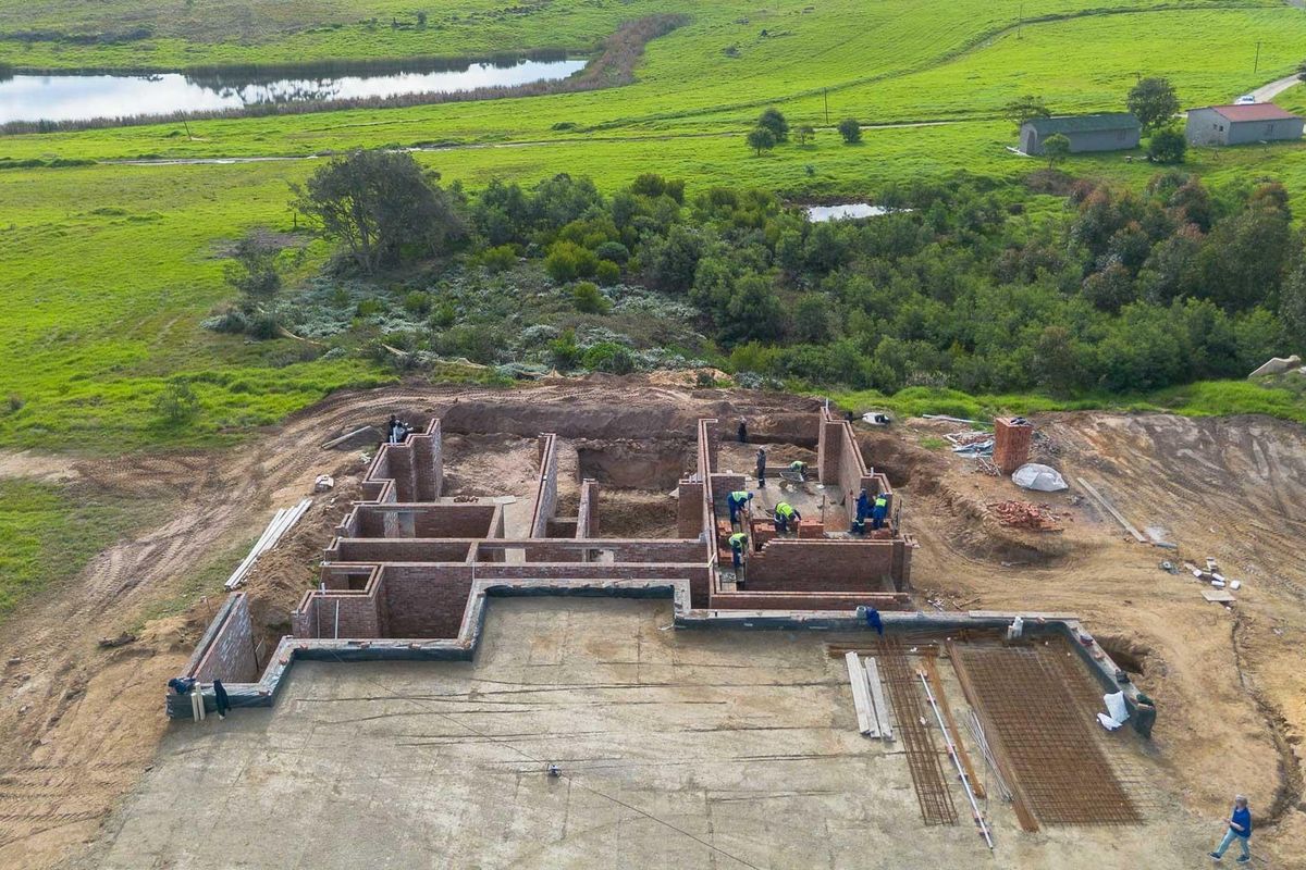 Aerial view of a residential property under construction, showing the brick foundation and concrete slab layout on a large rural plot.