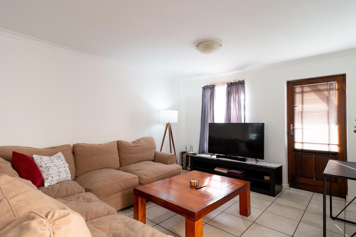 A comfortable living room featuring tiled flooring, coving, and direct access to an exterior door.