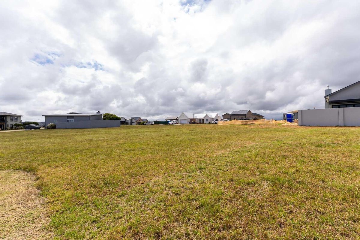 A vacant residential plot of land featuring established grass cover and surrounding boundary walls in a developed neighborhood setting.